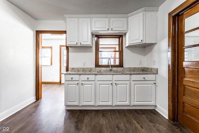 kitchen with baseboards, dark wood-style flooring, a sink, and white cabinetry