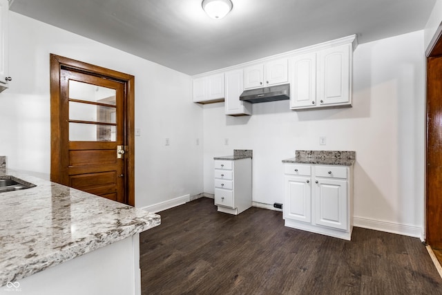 kitchen featuring baseboards, under cabinet range hood, dark wood-type flooring, and light stone counters