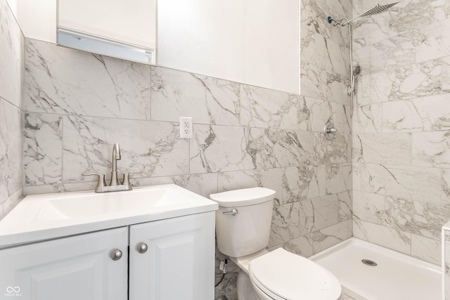 bathroom featuring a shower stall, toilet, vanity, and tile walls