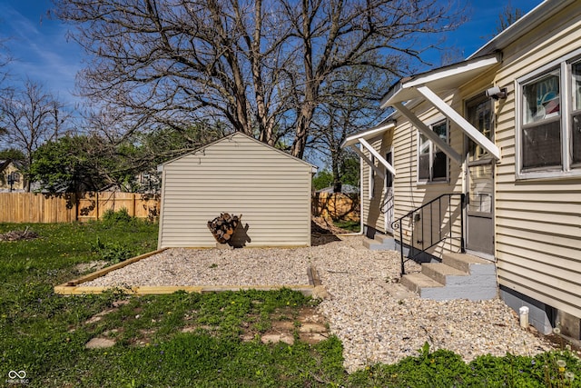 view of yard featuring a storage shed, fence, an outbuilding, and entry steps