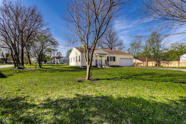 view of yard with an attached garage, fence, and driveway