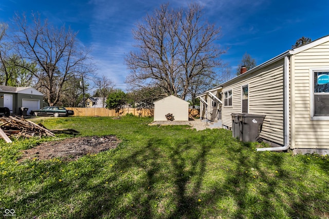 view of yard featuring an outdoor structure, fence, and a storage unit