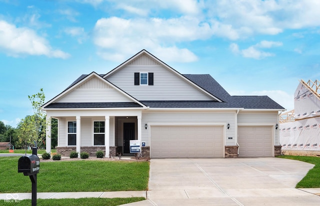 craftsman house with a garage, driveway, a front yard, and brick siding