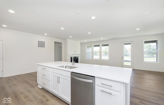 kitchen featuring visible vents, open floor plan, stainless steel dishwasher, light wood-style floors, and a sink