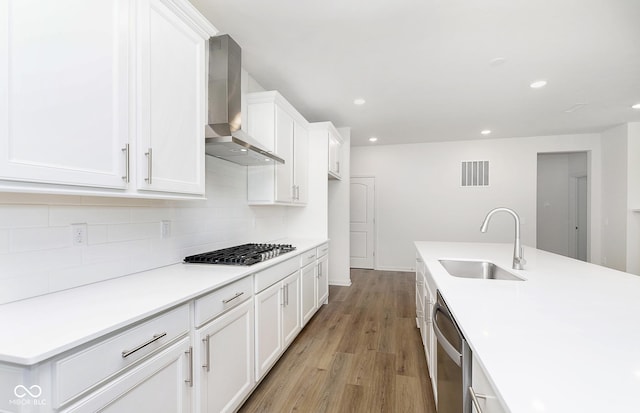 kitchen featuring a sink, visible vents, appliances with stainless steel finishes, decorative backsplash, and wall chimney exhaust hood