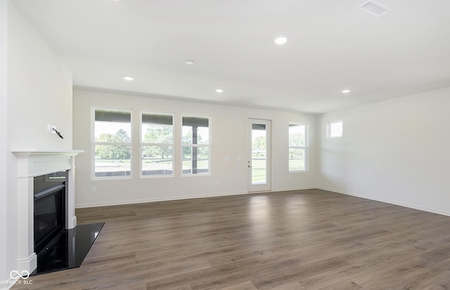 unfurnished living room featuring recessed lighting, visible vents, a fireplace with flush hearth, wood finished floors, and baseboards