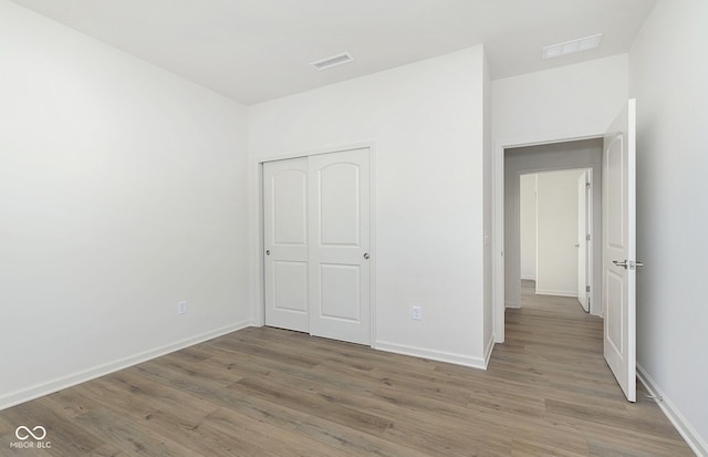 unfurnished bedroom featuring visible vents, light wood-style flooring, and baseboards