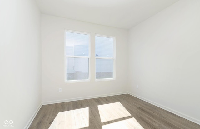 spare room featuring baseboards and wood finished floors