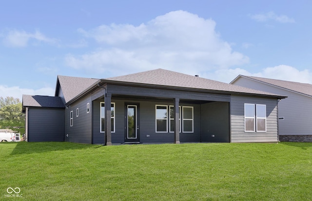 rear view of house featuring roof with shingles and a lawn