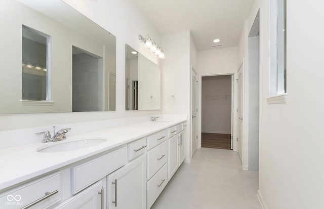 bathroom featuring visible vents, a sink, a spacious closet, and double vanity