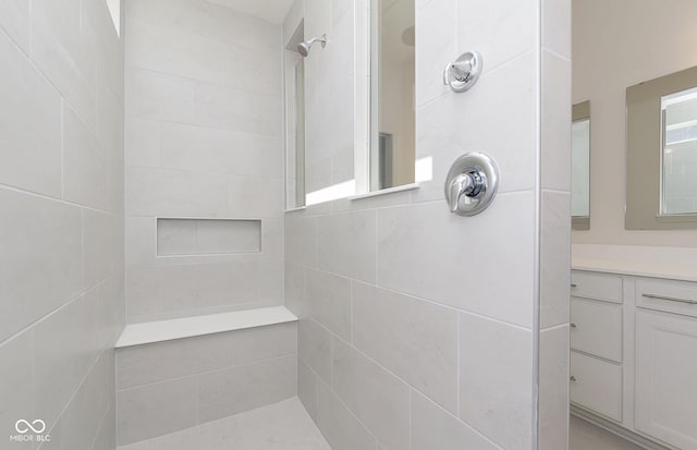 full bath featuring a tile shower and vanity