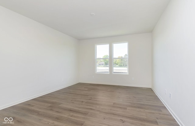 spare room featuring baseboards and wood finished floors