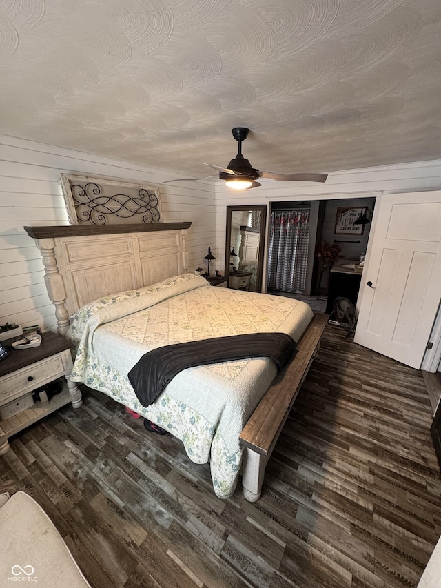 bedroom with wooden walls, a ceiling fan, and wood finished floors