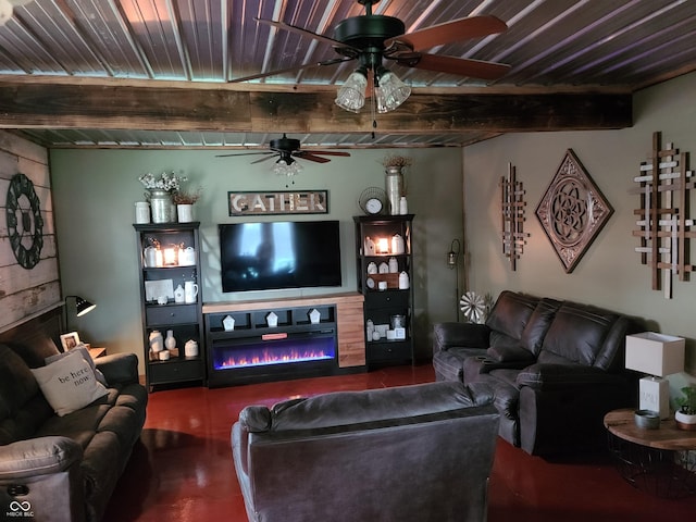 living area with concrete floors, a ceiling fan, beamed ceiling, and a glass covered fireplace