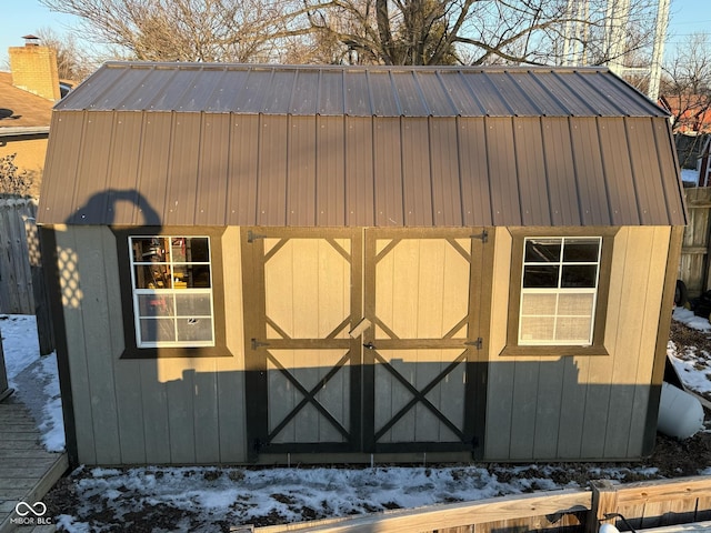 snow covered structure featuring a storage shed and an outdoor structure