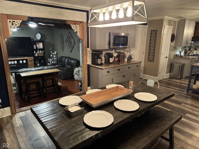 dining area with baseboards, ornamental molding, and wood finished floors