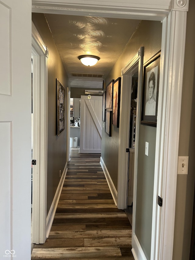 hallway with visible vents, baseboards, and dark wood-style flooring