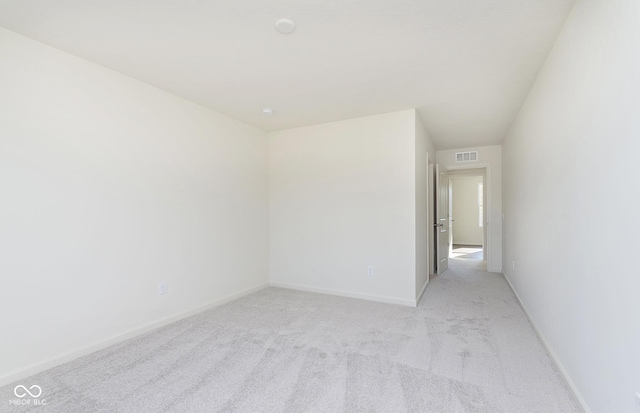 empty room with baseboards, visible vents, and light colored carpet