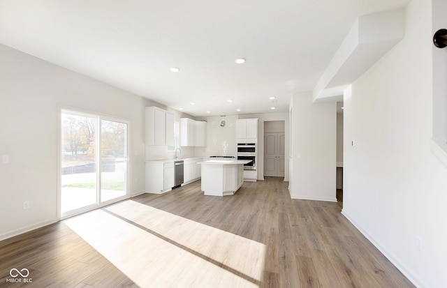 kitchen featuring open floor plan, light countertops, appliances with stainless steel finishes, a center island, and light wood finished floors