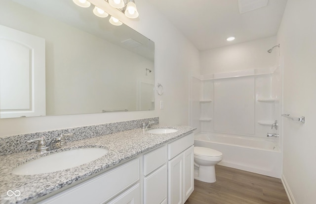 full bathroom with double vanity, a sink, toilet, and wood finished floors