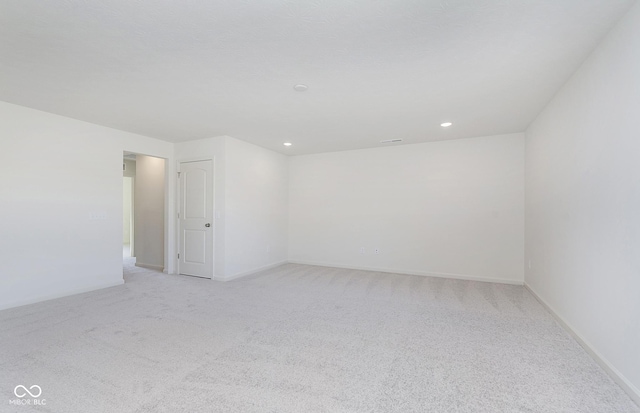 spare room featuring recessed lighting, baseboards, and light colored carpet