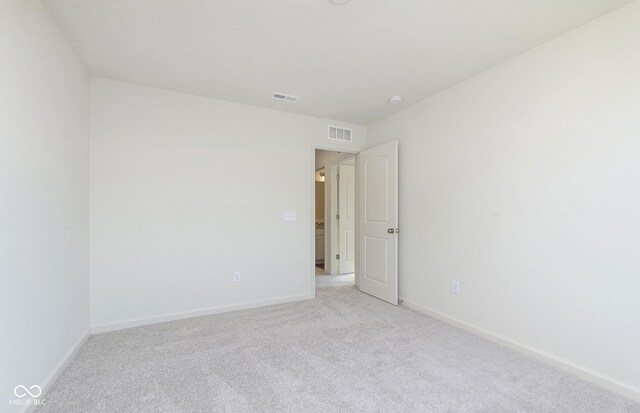 spare room with baseboards, visible vents, and light colored carpet