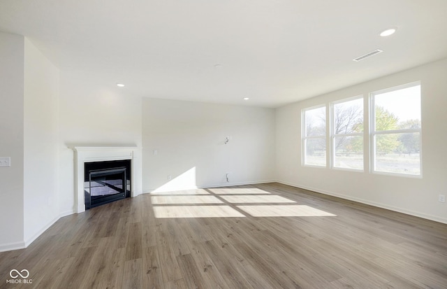 unfurnished living room featuring recessed lighting, a fireplace, wood finished floors, visible vents, and baseboards