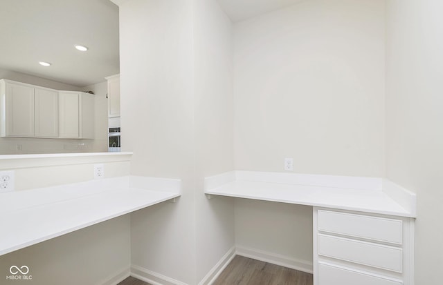 interior space with recessed lighting, baseboards, built in desk, and wood finished floors