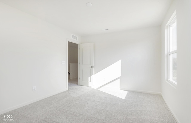 empty room with carpet, visible vents, and baseboards