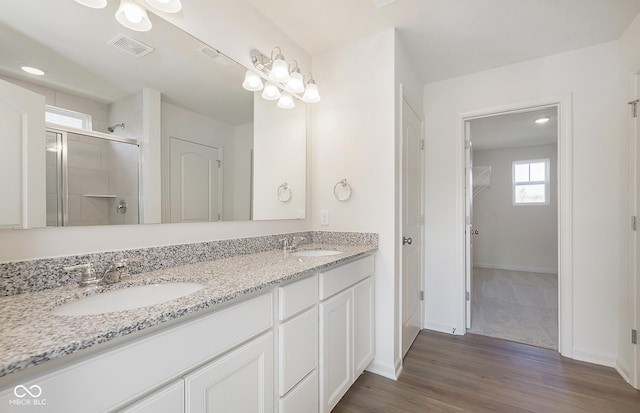 full bath featuring double vanity, a shower stall, visible vents, and a sink