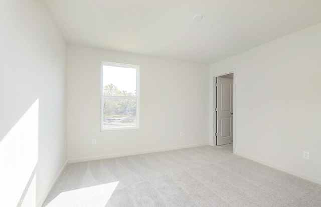 unfurnished room featuring light carpet and baseboards