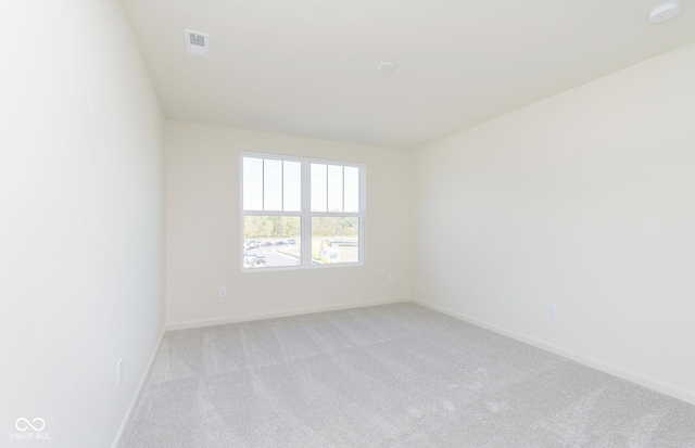 empty room featuring baseboards, visible vents, and light colored carpet