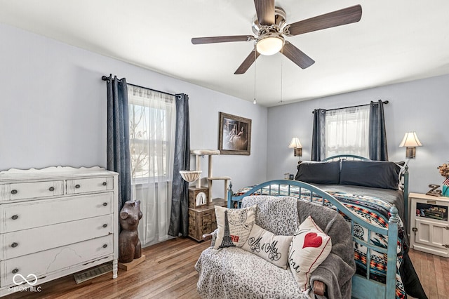 bedroom featuring ceiling fan, multiple windows, and light wood-style flooring