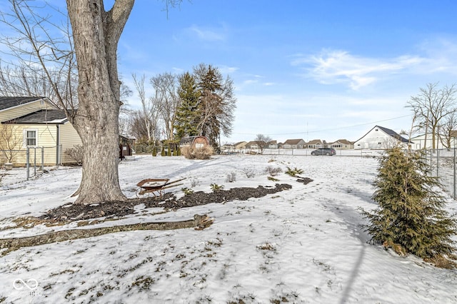 yard layered in snow with a residential view and fence