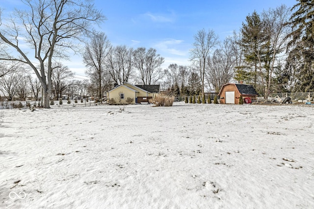 yard covered in snow with a garage, an outbuilding, fence, and a storage shed