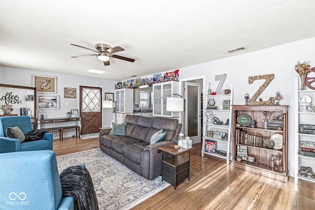 living area featuring ceiling fan, visible vents, and wood finished floors