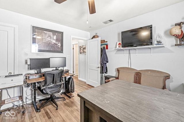 office with light wood-style flooring, visible vents, and ceiling fan