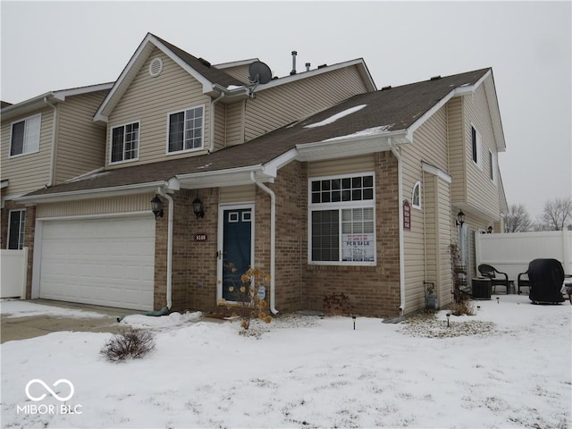 view of front of house with a garage, brick siding, and fence