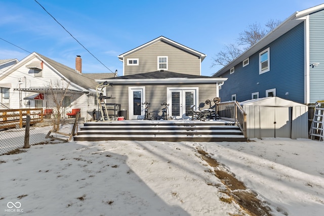 snow covered property featuring a storage unit, an outdoor structure, and fence