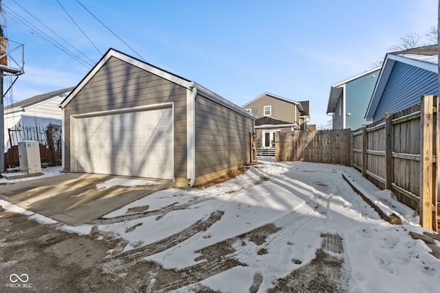 snow covered garage with a detached garage and fence