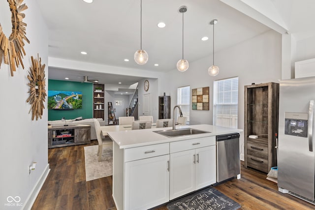 kitchen with stainless steel appliances, white cabinetry, hanging light fixtures, light countertops, and an island with sink