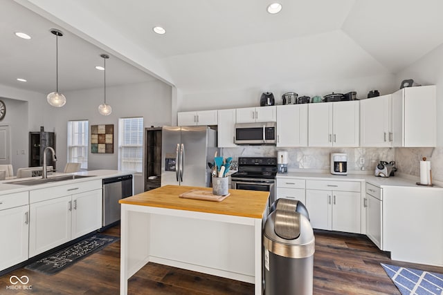 kitchen featuring stainless steel appliances, a kitchen island, a sink, white cabinets, and hanging light fixtures