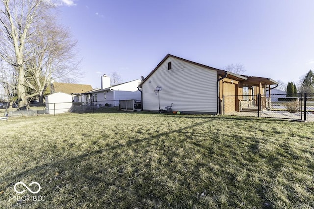 view of side of property with a gate, fence, and a lawn