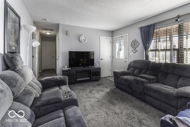 living area with a textured ceiling, dark colored carpet, and visible vents