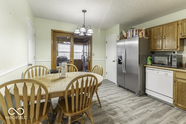 kitchen featuring black microwave, hanging light fixtures, light countertops, stainless steel refrigerator with ice dispenser, and dishwasher