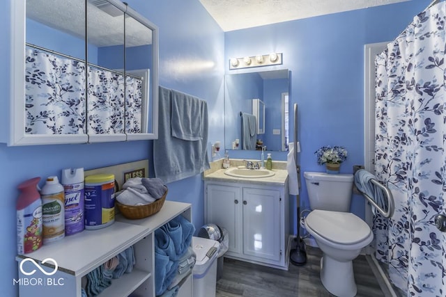 bathroom with a textured ceiling, toilet, wood finished floors, vanity, and a shower with curtain