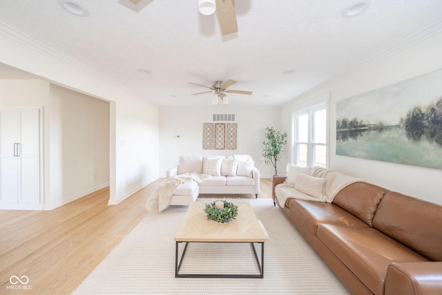 living area featuring ceiling fan, visible vents, light wood-style flooring, and crown molding