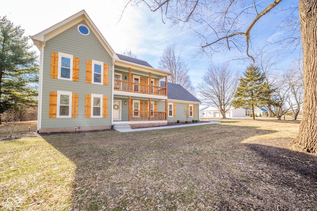 rear view of property with a balcony, covered porch, and a lawn