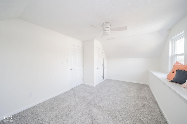 additional living space with baseboards, lofted ceiling, ceiling fan, a textured ceiling, and carpet floors