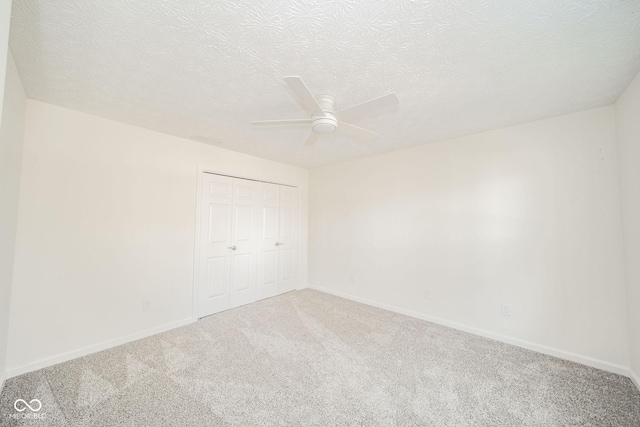 carpeted spare room featuring ceiling fan, a textured ceiling, and baseboards